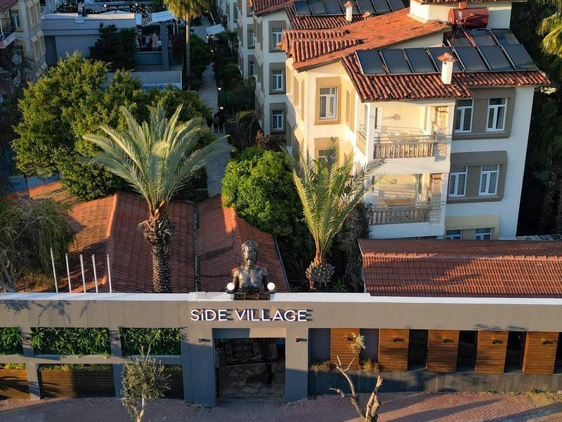 Moderner Hotelkomplex mit rotdachgedeckten Gebäuden und Palmen an sonnigem Tag.