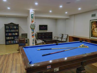 Table de billard avec surface en feutre bleu dans une pièce lumineuse avec des étagères et des sièges.