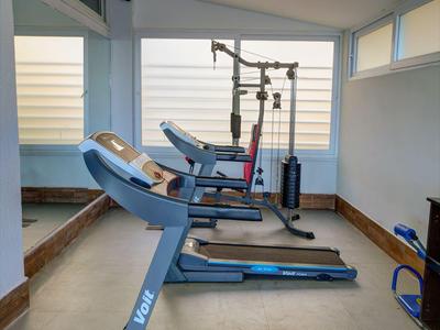 Intérieur d'une salle de sport moderne avec tapis de course et équipements près de grandes fenêtres.