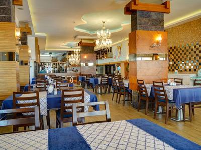 Großes Restaurant mit gedeckten Tischen, blauen Stühlen, Holzdekoration und Kronleuchtern.