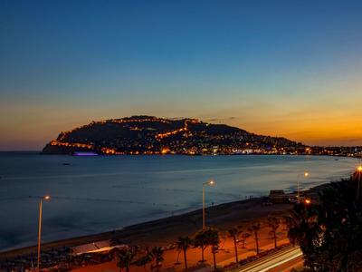 Insel bei Sonnenuntergang mit beleuchteten Gebäuden und ruhigem Meer im Vordergrund.