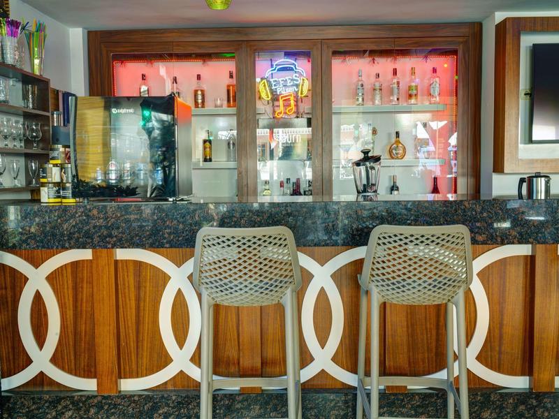 Moderne Bar mit Marmor-Theke, Holzfront und drei geflochtenen Barhockern in hellem Grau.