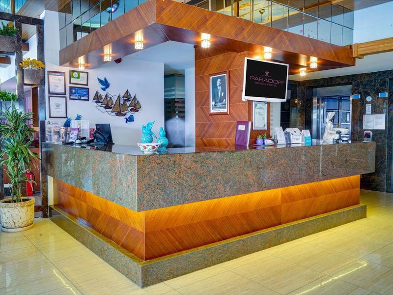 Moderner Empfangstresen mit Granitplatte, Holzakzenten und Pflanzen in heller Lobby.