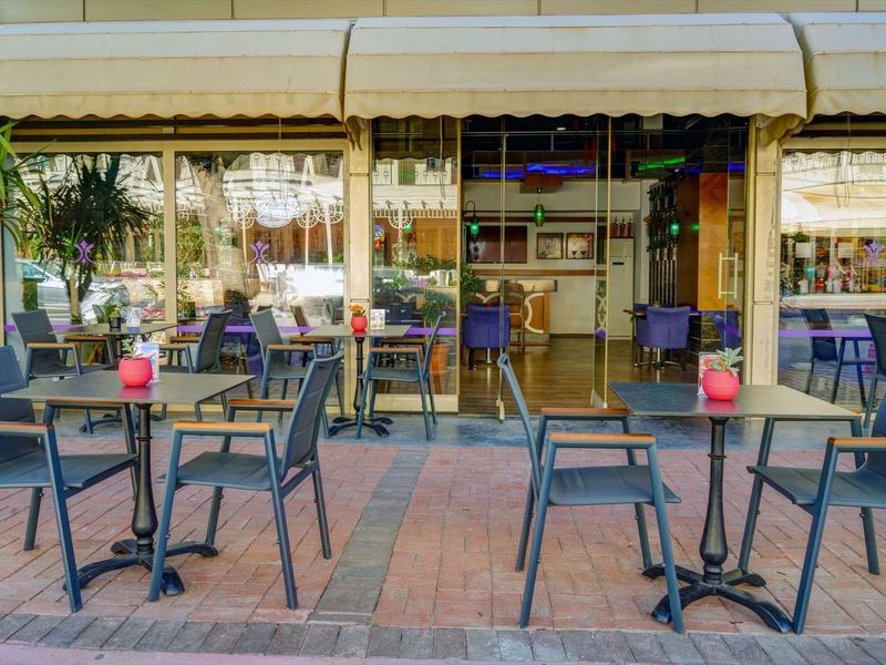 Außenbereich eines Cafés mit schwarzen Tischen und Stühlen auf rotem Pflaster.