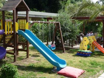 Bunter Kinderspielplatz mit Rutschen und Schaukeln auf einer Hotelwiese.