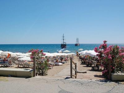 Strand mit Liegestühlen und Sonnenschirmen am Meer unter klarem Himmel.