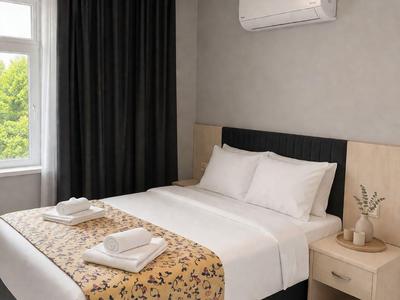 Gemütliches Hotelzimmer mit Doppelbett, weißer Bettwäsche und schwarzem Vorhang neben Fenster.