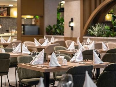 Elegantes Restaurant mit eingedeckten Tischen, weißen Servietten und bequemen Stühlen.
