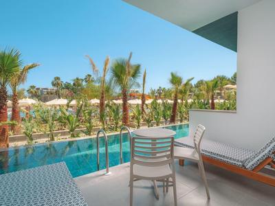 Balkon mit Lounge-Möbeln und Süßwasserpool, umgeben von Palmen unter blauem Himmel.