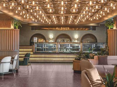 Modernes Café mit vielen runden Lampen, Holzvertäfelung und einer langen Theke im Hintergrund.