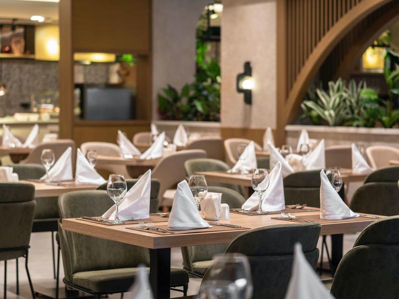 Espace de restaurant d'hôtel moderne avec des tables dressées et des chaises confortables.