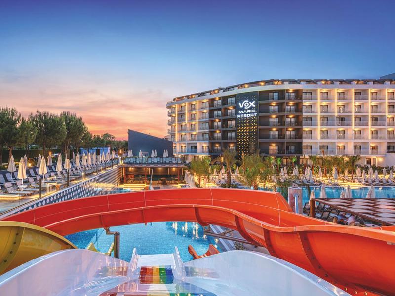 Complexe moderne avec piscine, toboggans et bar piscine au coucher du soleil.