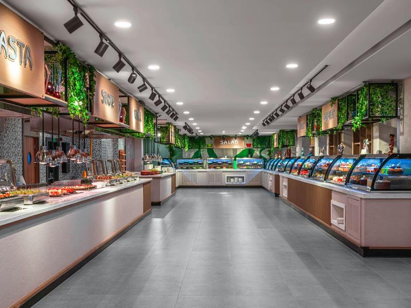 Restaurant buffet moderne avec large choix et décoration verte au plafond.