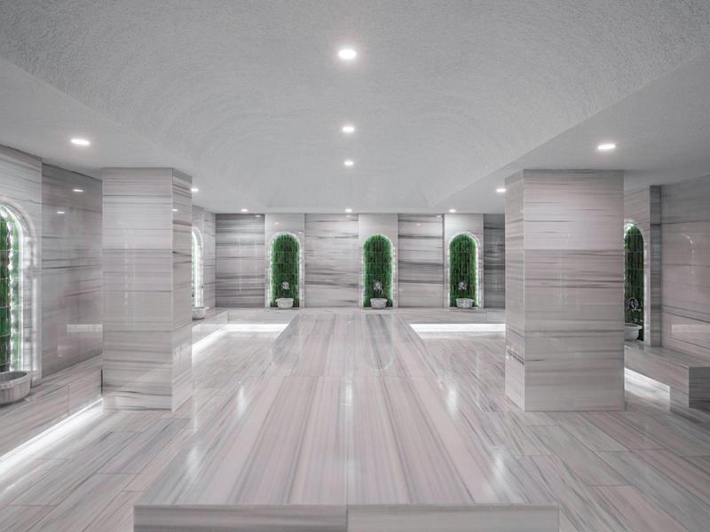 Grande salle de bien-être lumineuse avec murs en marbre et niches décorées.