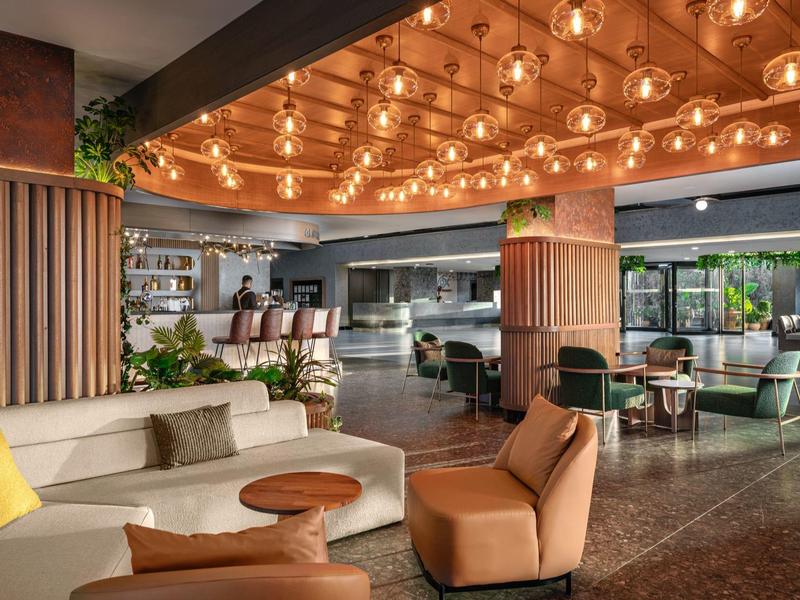 Hall d'hôtel moderne avec salon relaxant, fauteuils confortables et éclairage chaleureux au plafond.