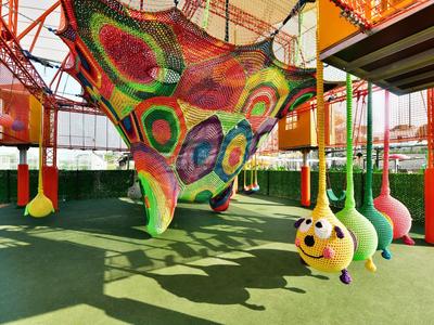 Barevná vnitřní herní plocha s houpacími sítěmi a hravými houpačkami ve tvaru zvířat.