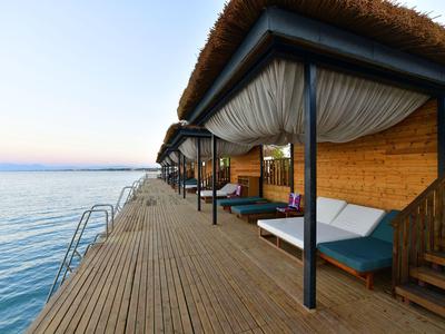 Houten pier met overwater bungalows met uitzicht op rustige zee bij zonsondergang.