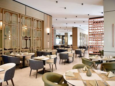 Elegantní hotelová restaurace s moderním posezením a stylovou stolní výzdobou.