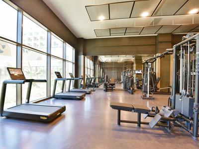 Moderne fitnessruimte met loopbanden en krachtapparatuur, grote ramen voor natuurlijk daglicht.