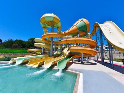 Kleurrijke waterglijbanen in een waterpark met een heldere blauwe lucht op de achtergrond.