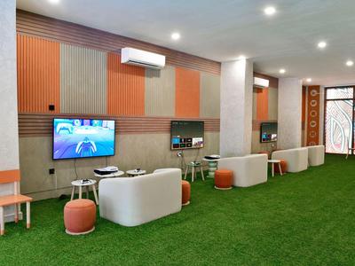 Een moderne lounge met witte zitplaatsen en groen tapijt in een hotelomgeving.