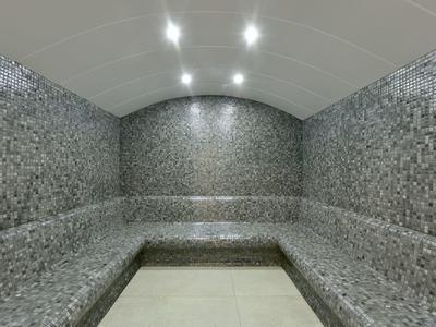 Moderní parní místnost se šedými mozaikovými dlaždicemi a integrovaným osvětlením.