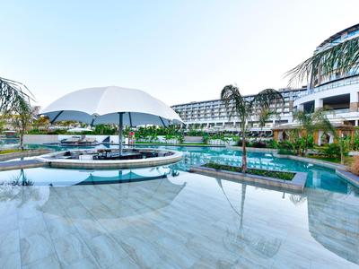 Modern buitenzwembad van hotel met parasols en palmbomen onder een heldere lucht