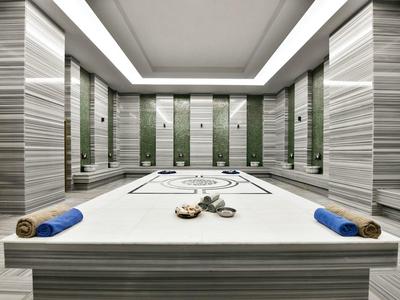 Moderní spa prostor s centrálním masážním stolem, ručníky a stylovým vybavením.