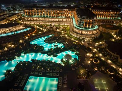 Luxusní hotel s osvětlenými bazény a upravenými venkovními prostory v noci