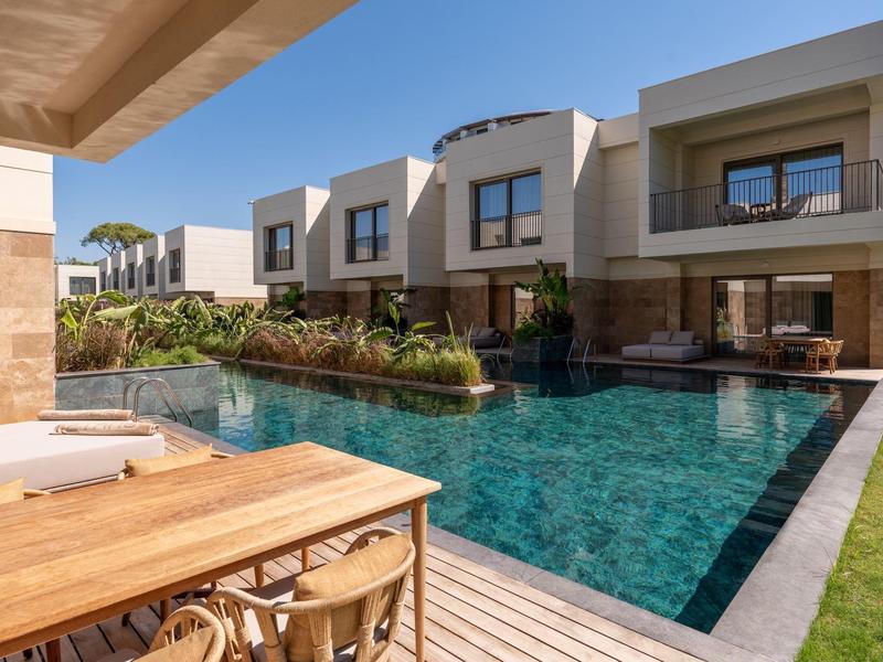 Moderní hotelový komplex s privátním bazénem a terasou pod modrou oblohou.