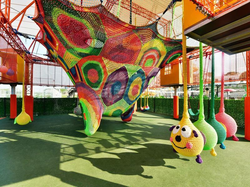 Barevná vnitřní herní plocha s houpacími sítěmi a hravými houpačkami ve tvaru zvířat.
