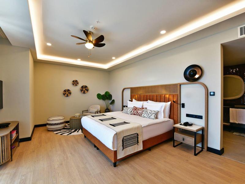 Moderní hotelový pokoj s velkou postelí, dřevěnou podlahou a dekorativními zdobeními na stěnách.