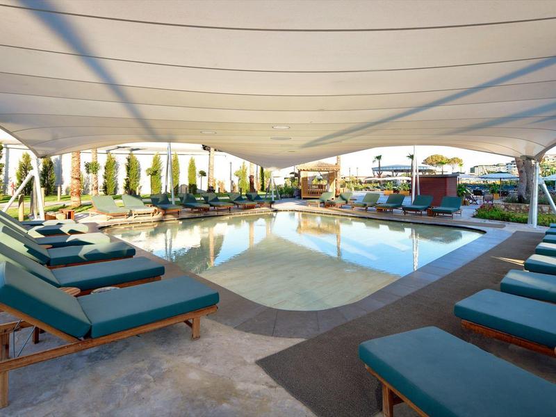 Luxusní hotelová bazénová plocha s pohodlnými lehátky a slunečními stříškami za denního světla.