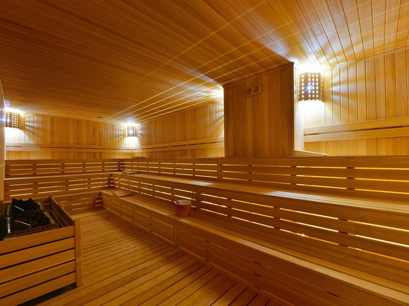 Pohodlná dřevěná sauna s vícestupňovými lavicemi a jemným stěnovým osvětlením.