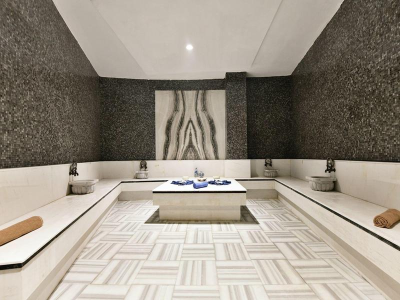 Elegantní moderní wellness prostor s béžovým posezením a stylovým zdobením stěn.