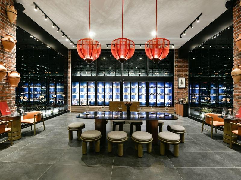 Moderní jídelna s tmavou podlahou, červenými lampami a nočním výhledem na město.