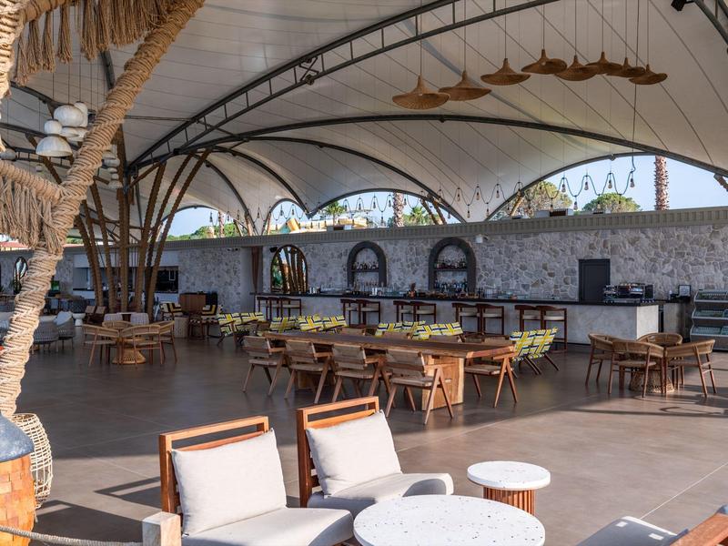 Velká krytá venkovní plocha s jídelními stoly a židlemi v hotelu.