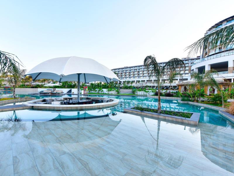 Moderní venkovní bazén s deštníky a palmami v hotelu za denního světla