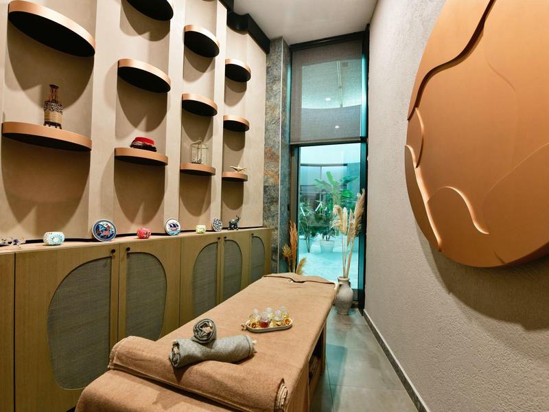 Útulná lázeňská místnost s masážním stolem, dekorativními prvky a oknem s výhledem ven.