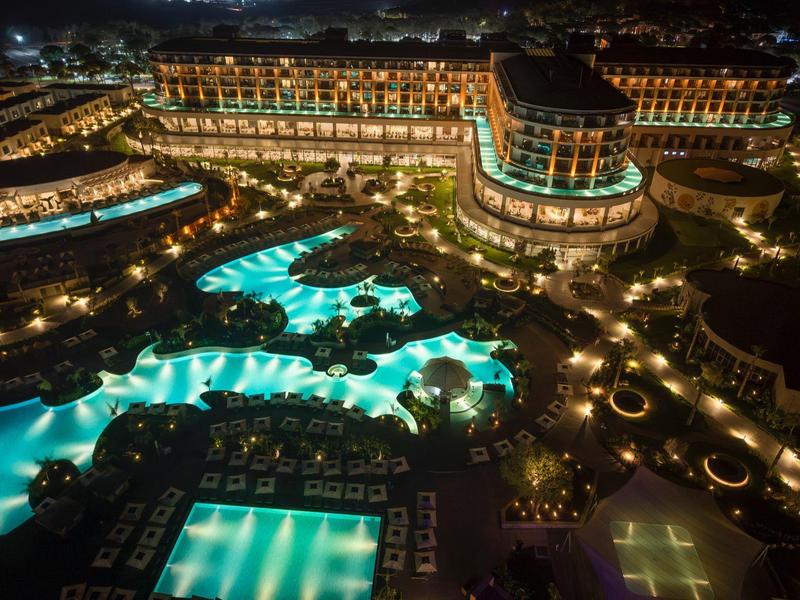 Luxusní hotel s osvětlenými bazény a upravenými venkovními prostory v noci