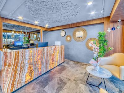 Modern hotel reception with illuminated front desk, decorative mirrors, and cozy seating area.