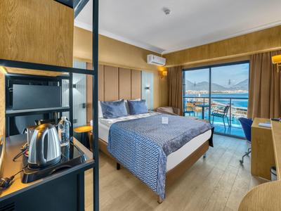 Modern hotel room with double bed, balcony, and sea view.