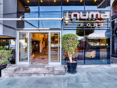 Entrada moderna del hotel con puertas de vidrio y plantas en macetas negras