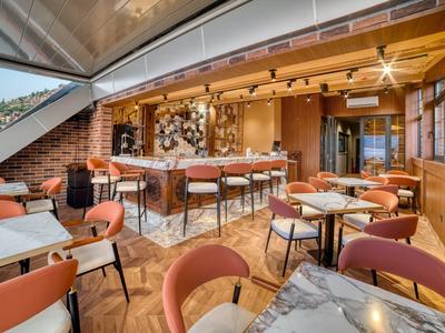 Modern restaurant interior with marble tables, comfortable chairs, and a bar bathed in warm lighting.