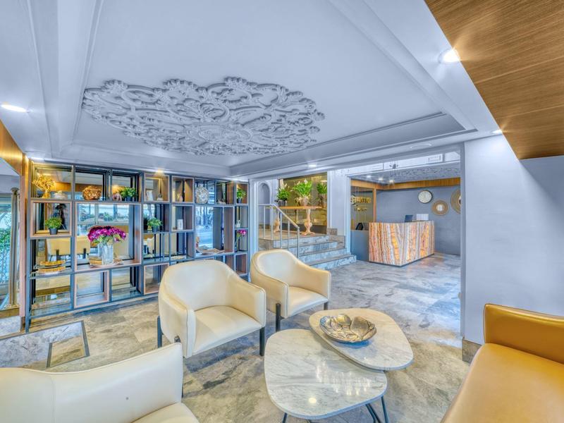 Bright and modern hotel lobby with cozy armchairs and decorative shelving.