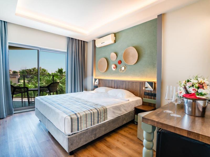 Hotelkamer met tweepersoonsbed, balkon met uitzicht op groen, en moderne inrichting.