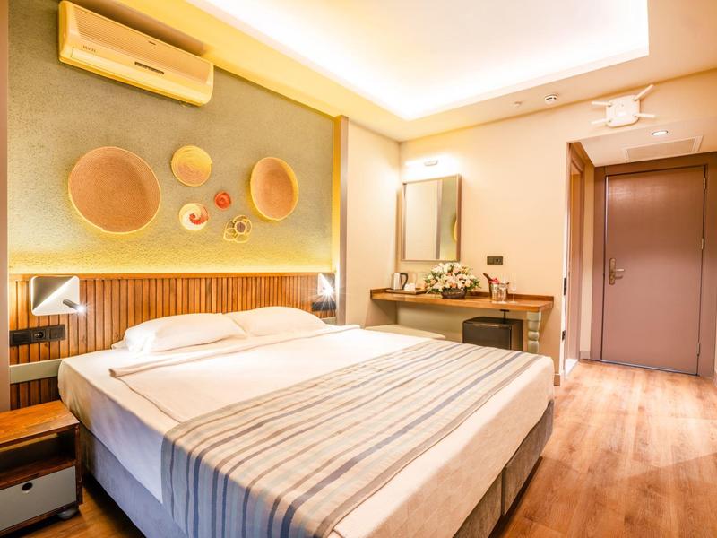 Gezellige hotelkamer met groot bed, houten vloer, ronde wanddecoratie en een kaptafel.