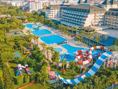 Gran resort con varias piscinas, toboganes acuáticos y jardines verdes bajo el sol.