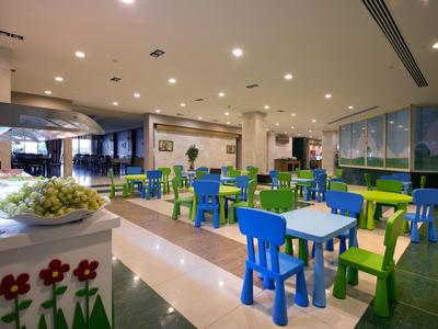 Indoor dining area with colorful blue and green chairs and tables in a bright, spacious room.
