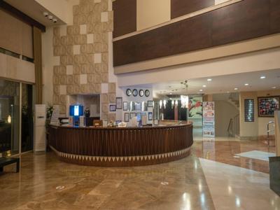 Elegant hotel reception with curved wooden desk and polished marble floor under warm lighting.